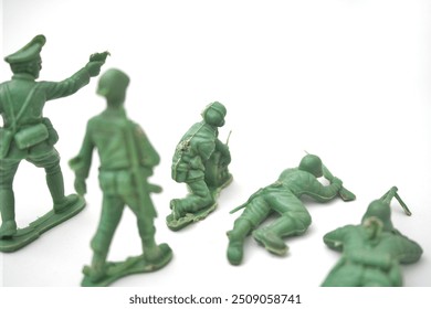 Green plastic toy soldiers arranged in a playful line on a white background. - Powered by Shutterstock