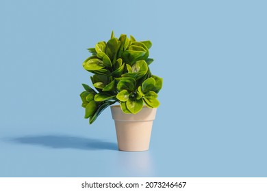 Green plastic tree in the cream color pot isolated on a blue background with copy space