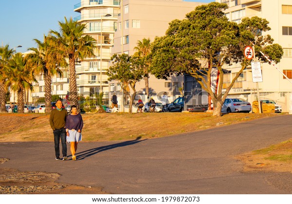 Green Point, Cape Town, South Africa -\
17-05-2021\
\
Green Point sea shore during sun down. Palm trees,\
people and parking in foreground.\

