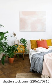 Green Potted Houseplants Close To Vintage Night Table And Bed With Crumpled Plaid, Colorful Cushions. The Style Of The 60s Concept. Bright Bedroom In Apartment With Bohemian Chic Interior Design