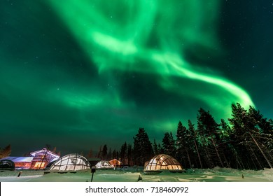 Green powerful bright aurora above igloo house in Finland