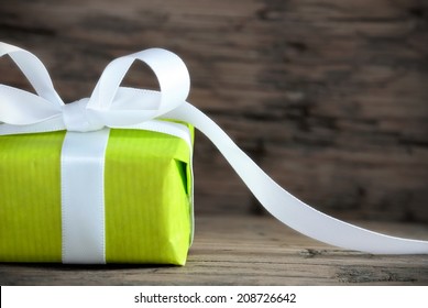 Green Present On Wood With White Ribbon And Copy Space