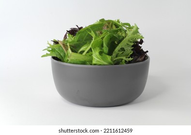 Green And Purple Salad Lettuce Leaves In A Grey Bowl On A White Background