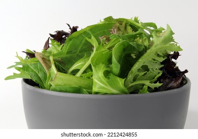 Green And Purple Salad Lettuce Leaves In A Grey Bowl On A White Background
