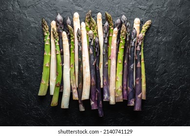 Green, Purple And White Asparagus Sprouts On Black Board Top View Flat Lay. Food Photography