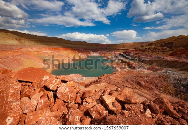 Green\
quarry lake in bauxite mine. On blue sky with clouds in summer day.\
Aluminium ore open-cut (open cast, open-pit)\
mine