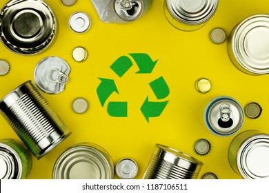 Green Recycle Reuse Sign Symbol With Metal Aluminium Cans, Covers, Jars On Yellow Background. Eco Ecology Environment Garbage Recycling Concept