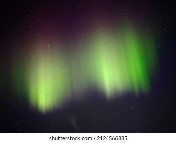 Green And Red Aurora Borealis On Night Sky.