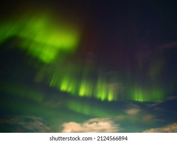 Green And Red Aurora With Clouds In The Night.