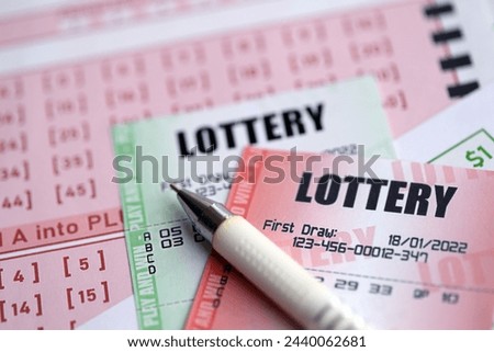 Green and red lottery tickets with pen on blank bills with numbers for playing lottery close up
