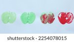 Green, red and red-green stamped apples in a row. Stamped with real applehalve and fingerpaints on white paper.