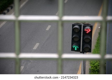 Green and red traffic light with green arrow light up in city , not allows car to turn right 
