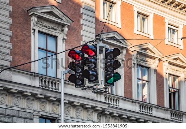 Green and red traffic lights turned in different\
directions of the intersection on background of ancient building in\
european city.