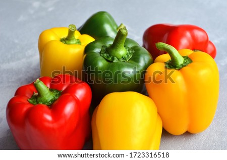 Green, red and yellow bell pepper on grey stone background. Organic healthy food