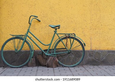 Green Retro bike on a bright yellow wall background on the street