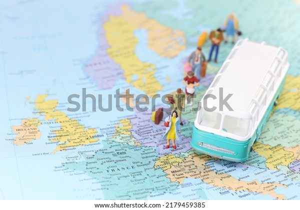A green retro bus on a map of Europe with\
miniature people.