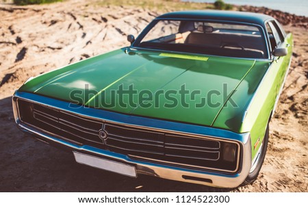 Green retro car is standing on the beach. Vintage classic car. Old and stylish. Muscle car.
