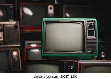 Green retro old television with blank screen in the room, many old TVs background. Vintage style filtered photo