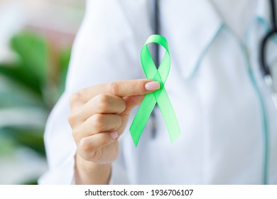 Green ribbon in hand as a symbol to awareness Lymphoma cancer - Shutterstock ID 1936706107