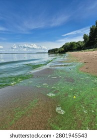 Green River Wave with Algae Rolling onto a Sandy Bank Under a Cloudy Blue Sky