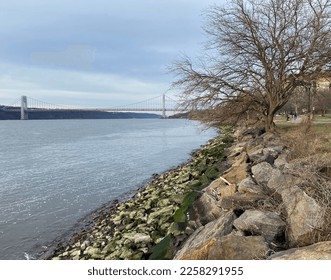 Green rocks exposed during low tide on the Hudson River on a February afternoon in Riverside Park in Upper Manhattan, New York City, USA - Shutterstock ID 2258291955