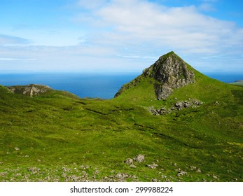 Green Rocky Hills On The Isle Of Skye In Scotland With Blue Ocean In The Background.