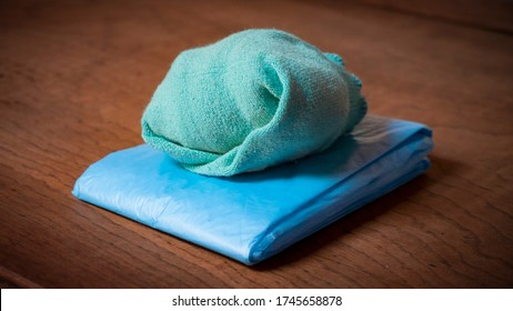 Green rolled sock on folded blue plastic bag on a wooden sideboard