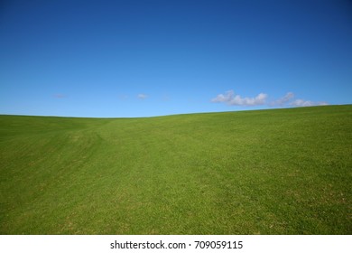 Green rolling hills against a deep blue sky