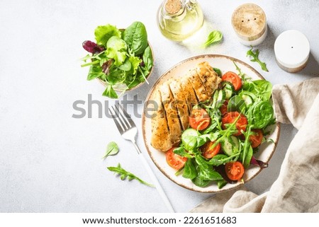 Green salad with chicken fillet on white.