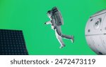 Green Screen Chroma Key Studio Production: Male Astronaut in a Costume in Outer Space. Trained Professional Spaceman Performing Extravehicular Activity Next to a Satellite and Solar Panels