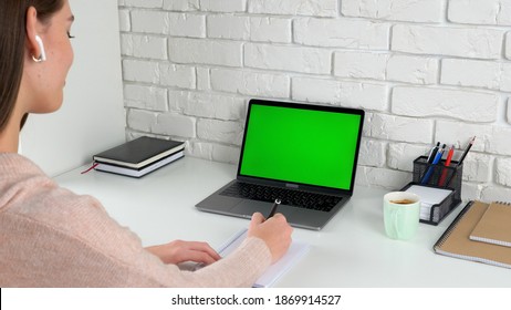 Green Screen Laptop Computer Concept: Online Remote Distance Learning Education By Web Cam Video Call Conference. Smiling Woman Student At Home Study Listens Teacher Writes Information In Notebook