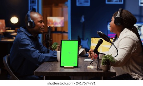 Green screen tablet in front of show host recording podcast, enjoying cup of coffee and nice conversation with guest. Mockup device in professional studio used for podcasting live session with woman - Powered by Shutterstock