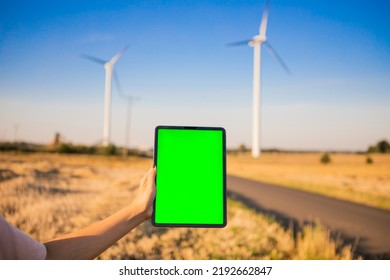 Green Screen Tablet On The Windmills Background. Chroma Key. Windmills Green Energy