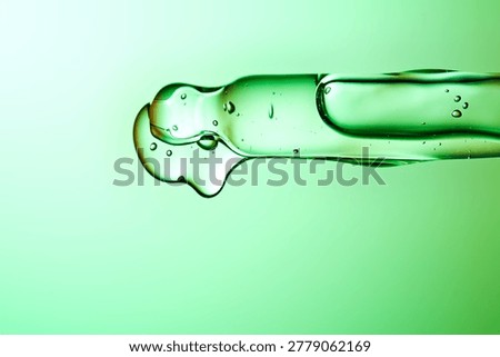 Green serum dropping from a precise laboratory pipette
