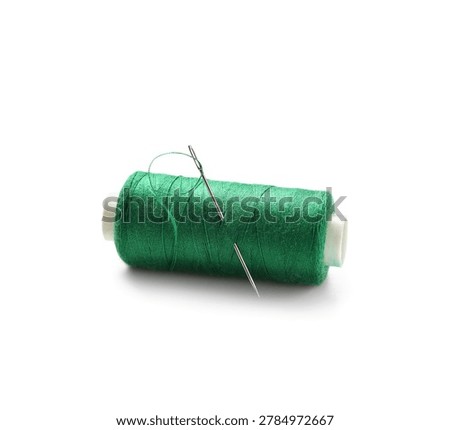 Green sewing thread spool with needle isolated on white background, closeup