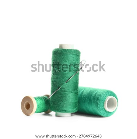 Green sewing thread spools with needle isolated on white background, closeup