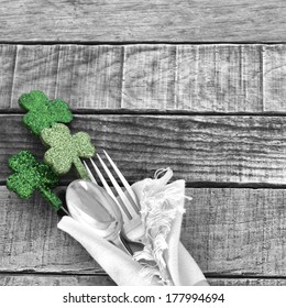 Green Shamrocks With Black And White Fork And Spoon And Napkin On Rustic Wood Board Background For St. Patricks Day Celebration.  Room Or Space For Copy, Text, Words.