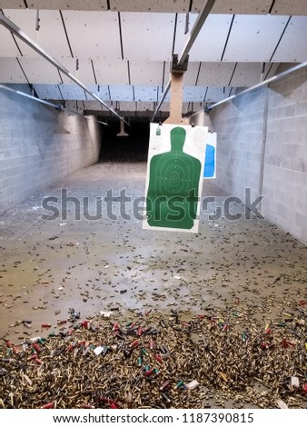 Green shooting range target over a lot of empty cartridge. Firearm ammunition, empty bullet, shots or slug.