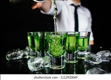 Green Shots At The Nightclub.
Bartender Pouring Strong Alcoholic Drink Into Small Glasses On The Bar.
Green Cocktails At The Club. Shooter Cocktail.