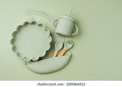 Green Silicone Baby Bib And With Plate And Drinking Cup. Serving Baby. First Baby Accessories For Dinner. Top View, Flat Lay