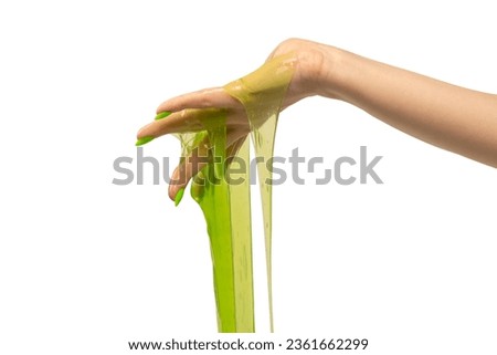 Green slime toy in woman hand with green nails isolated on a white background. 