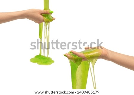 Green slime toy in woman hand with green nails isolated on a white background. 