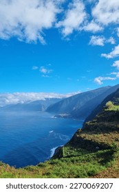 Green slopes of the mountains of Madeira island. The waves of the Atlantic Ocean wash the coast of the island