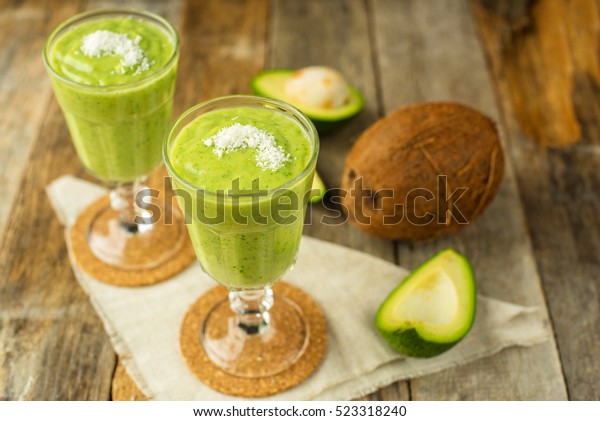 Green smoothie with avocado and coconut on a\
rustic wooden background