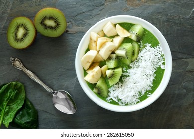 Green smoothie bowl with spinach, bananas, kiwi and coconut on a slate background - Powered by Shutterstock