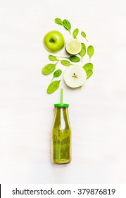 Green Smoothie Drink In Bottle With Straw  And  Ingredients ( Spinach,apple, Lime )  On White Wooden Background, Top View