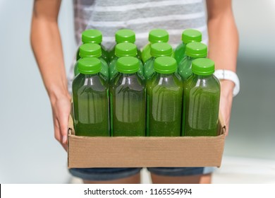 Green smoothie juice bottles box of cold pressed vegetable juices. Woman holding delivery box. Health trend for cleansing of organic raw juices. Juicing for diet cleanse detox.