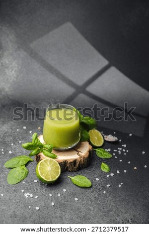 Green smoothie with lime and spinach on wood slice with salt crystals and basil leaves