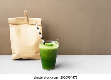 A Green Smoothie In A Plastic Cup And A Lunch Bag On A Table. Close Up, Healthy Eating, To Go. 