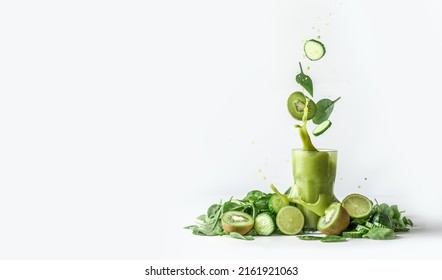 Green smoothie splashing in glass and flying ingredients: cucumber,kiwi and spinach leaves at white background with heap of green fruit and vegetable. Border. Front view. - Shutterstock ID 2161921063